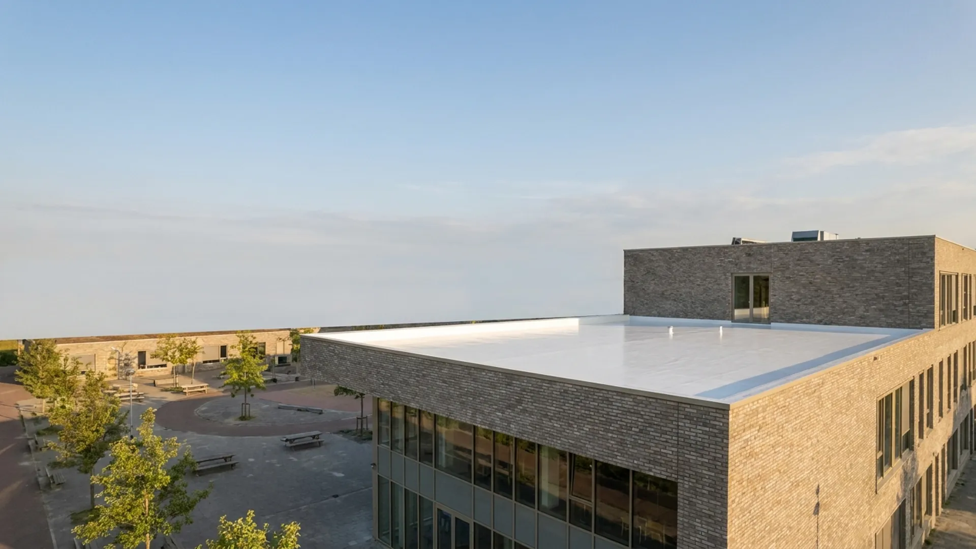 Wit gecoat plat dak van een schoolgebouw met schoolplein