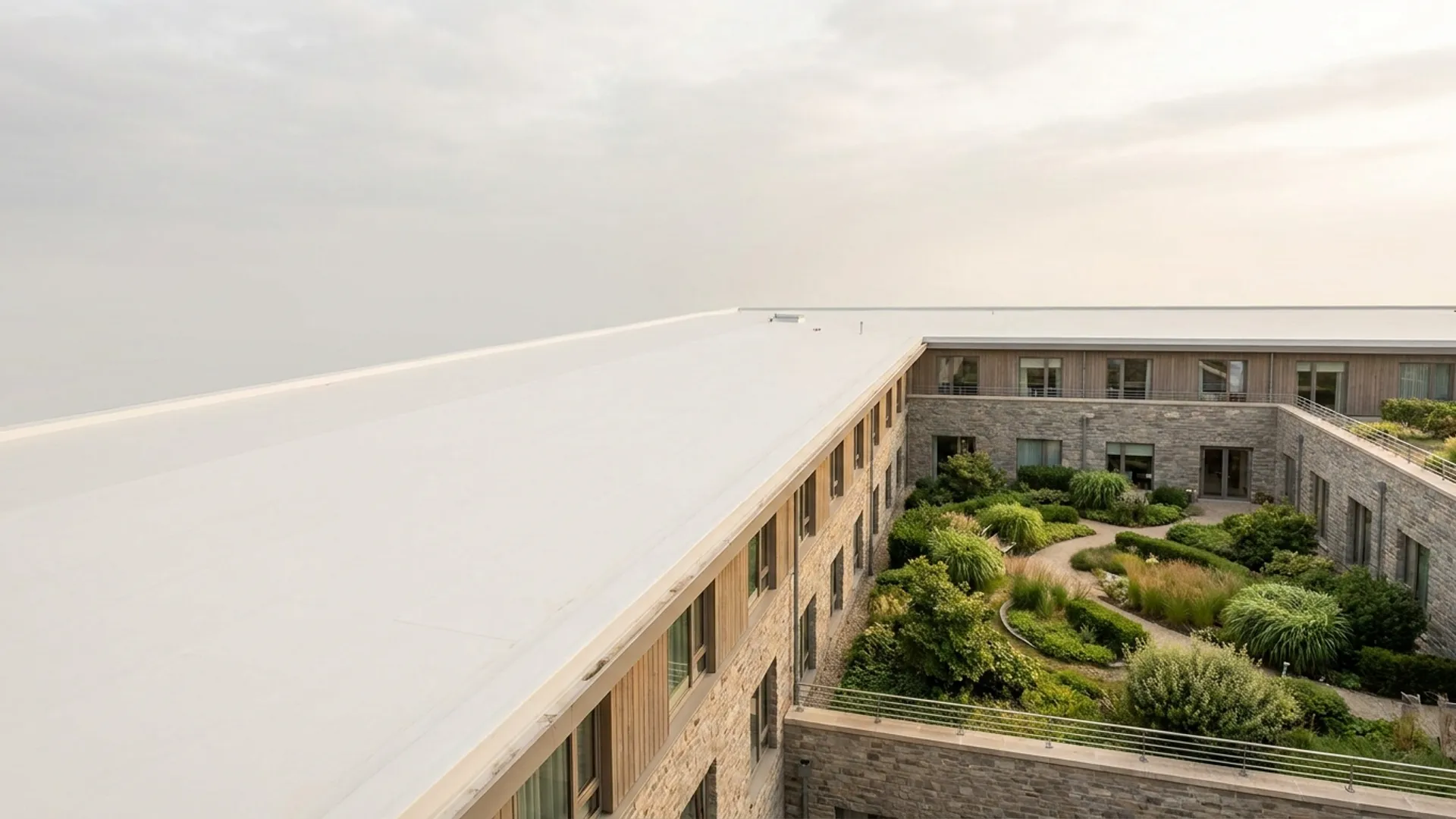 Wit gecoat dak van een zorggebouw met een groene binnentuin